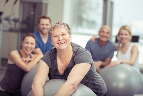 Ältere Frau auf Gymnastikball beim Sport Ältere Frau auf sitzt auf einem Gymnastikball und lächelt.