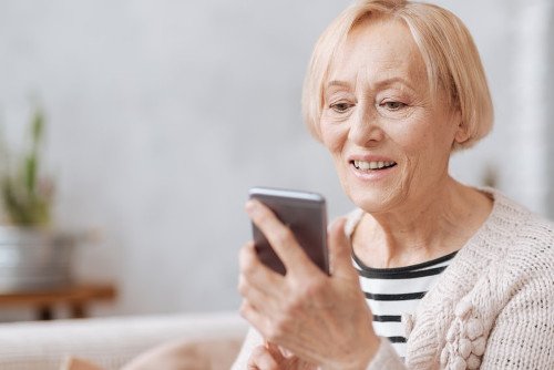Ältere Frau tippt auf Smartphone Frau benutzt Ihr Smartphone zur Bedienung einer EGK-App.