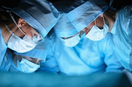 Ärzte bei der OP Vier Ärzte stehen über einem Patienten und operieren.
