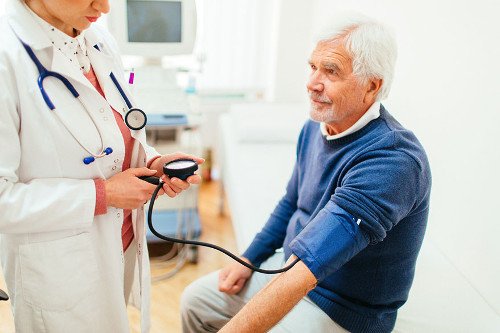 Ärztin-mit-älterem-Patienten Ärztin misst bei älteren Herrn den Blutdruck.